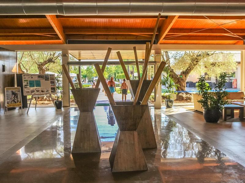 Open hotelreceptie met houten balken en grote ramen die natuurlijk licht binnenlaten.