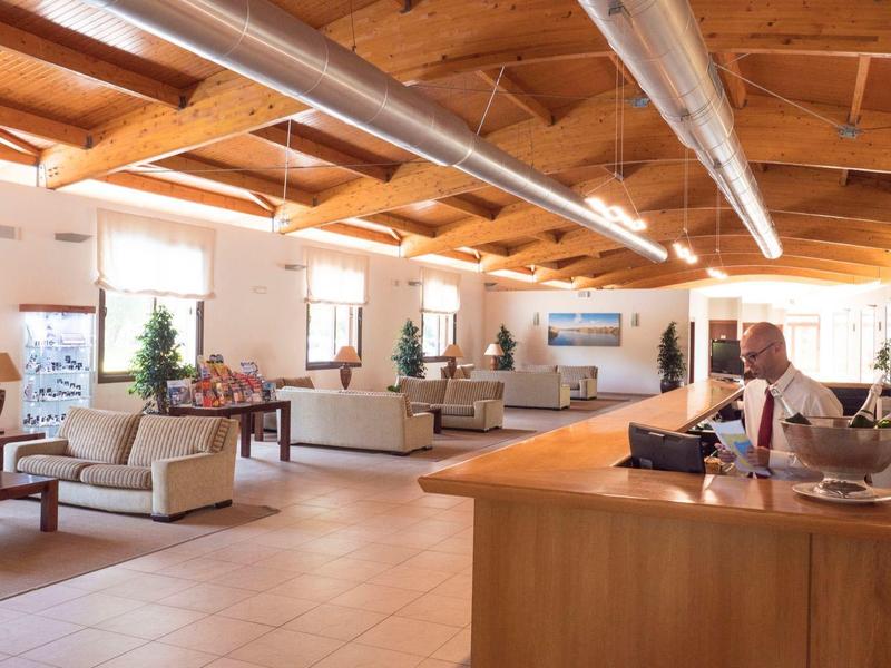 Hotelreceptie met balie, zitgedeeltes en houten balkenplafond op de achtergrond.