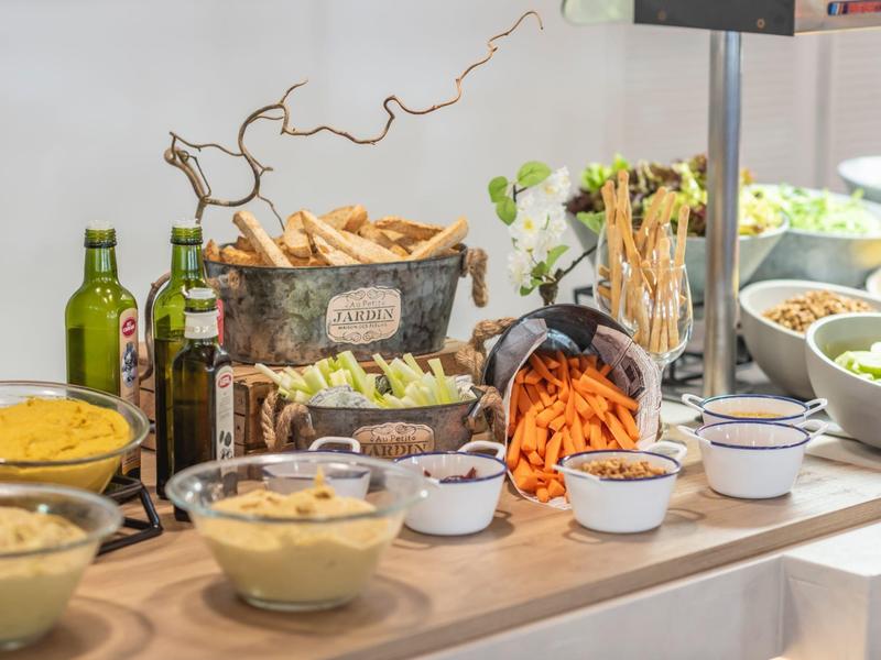 Buffet met verse groenten, dips, stokbrood en olijfolie op een houten tafel.