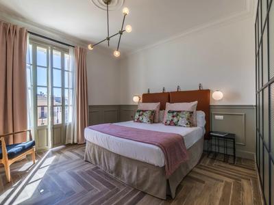 Gezellige hotelkamer met tweepersoonsbed, zithoek en balkon bij daglicht.
