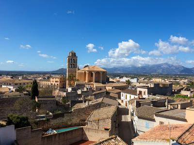 Veduta della città con vecchi edifici, una chiesa e montagne sullo sfondo sotto un cielo limpido.