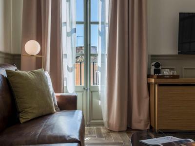 Accogliente zona soggiorno con divano in pelle, cuscini, tende e vista su finestra e città.