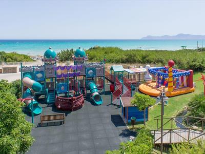 Barevné hřiště se skluzavkami a lezeckými strukturami u pláže s výhledem na moře.