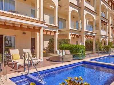 Venkovní prostor hotelu s terasami, bazény a posezením ve teplém slunečním světle.