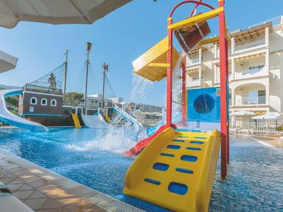 Barevné vodní hřiště s tobogány a lodí v bazénu před hotelem.