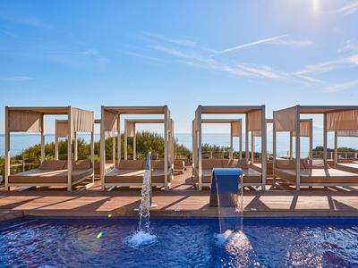 Luxury beach beds by a pool overlooking the sea under a blue sky