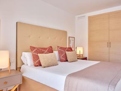 Světlo ložnice s manželskou postelí, béžovým čelem postele, nočními stolky s lampami a skříní.