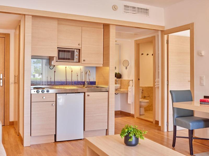 Moderně zařízený kuchyňský kout s mikrovlnnou troubou, lednicí a výhledem do sousední koupelny.