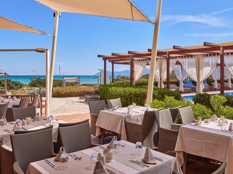 Elegantní restaurace u pláže se slunečnými sedadly a výhledem na modré moře.