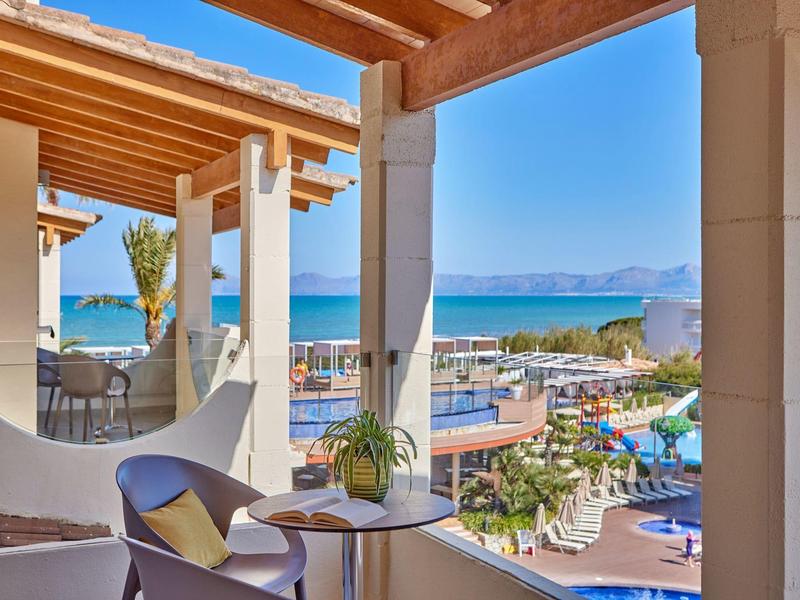 Balkon s posezením a výhledem na moře v hotelu za slunečného počasí.