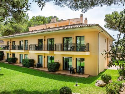 Zweistöckiges gelbes Hotelgebäude mit Balkonen und Grünflächen im Vordergrund.