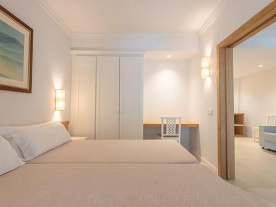 Helles Hotelzimmer mit Doppelbett, Schreibtisch und angrenzendem Wohnbereich.