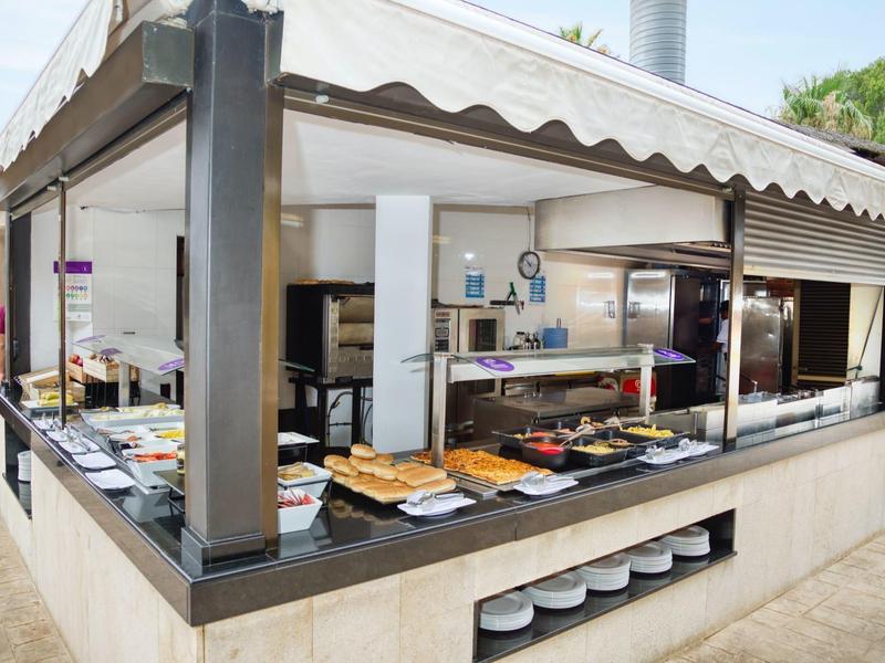 Buffet abierto con varios platos en un área exterior moderna de un hotel.