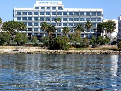 Nowoczesny biały budynek hotelu przy wodzie z czystym niebieskim niebem w tle.