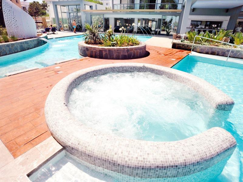 Nowoczesny obszar basenu z okrągłym jacuzzi, drewnianym tarasem i przyległą rzeką w hotelu.