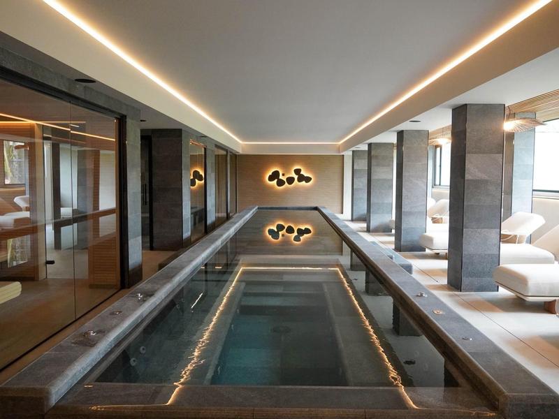 Nowoczesna strefa spa z krytym basenem, leżakami i ciepłym oświetleniem.