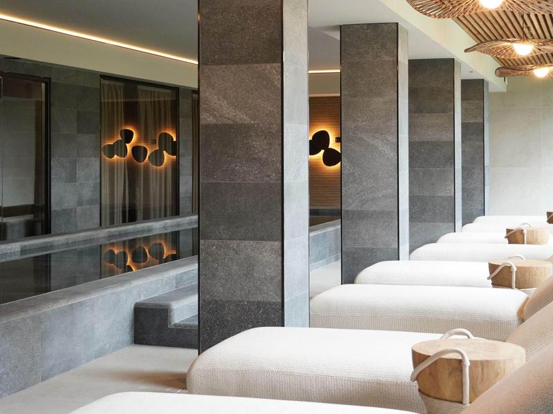 Nowoczesne spa z kilkoma leżakami i stonowanym oświetleniem w luksusowym otoczeniu.