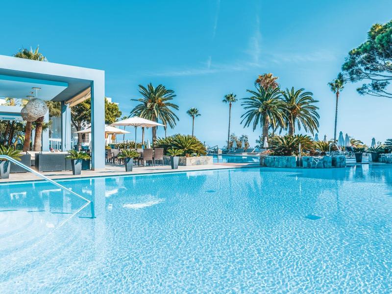 Czysta woda w basenie z palmami i leżakami pod niebieskim niebem