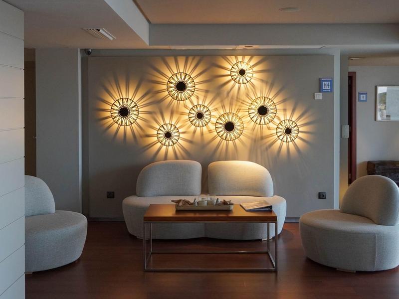 Przytulny kącik do siedzenia z nowoczesnymi lampami w kształcie słońca na ścianie w hotelu