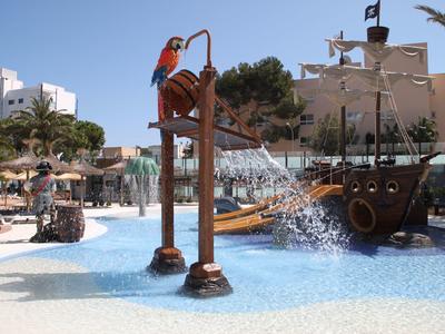 Plenerowy wodny plac zabaw o tematyce pirackiej z basenem, zjeżdżalniami i rzeźbami, jasny dzień.