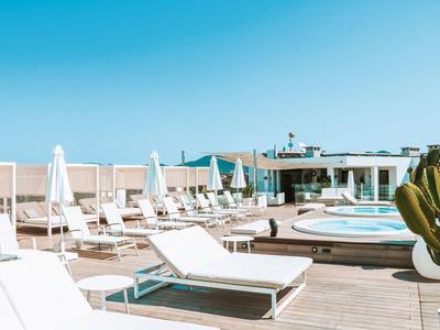 Słoneczny taras na dachu z białymi leżakami i okrągłymi basenami pod bezchmurnym niebem