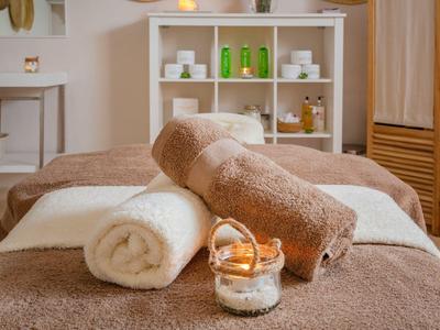 Gemütlicher Spa-Raum mit braunen Massageliegen, weißen Handtüchern und Aromakerzen.