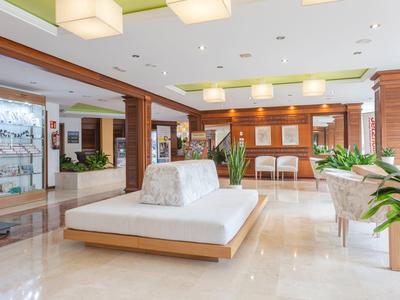 Helle Hotellobby mit modernen Sitzmöbeln, Pflanzen und warmem Holzdekor.
