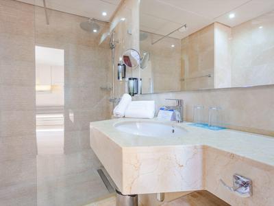 Helles Badezimmer mit cremefarbenem Marmor, Doppelwaschbecken und großen Spiegeln.