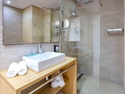 Nowoczesna łazienka z umywalką, lustrem i prysznicem w jasnych kolorach.