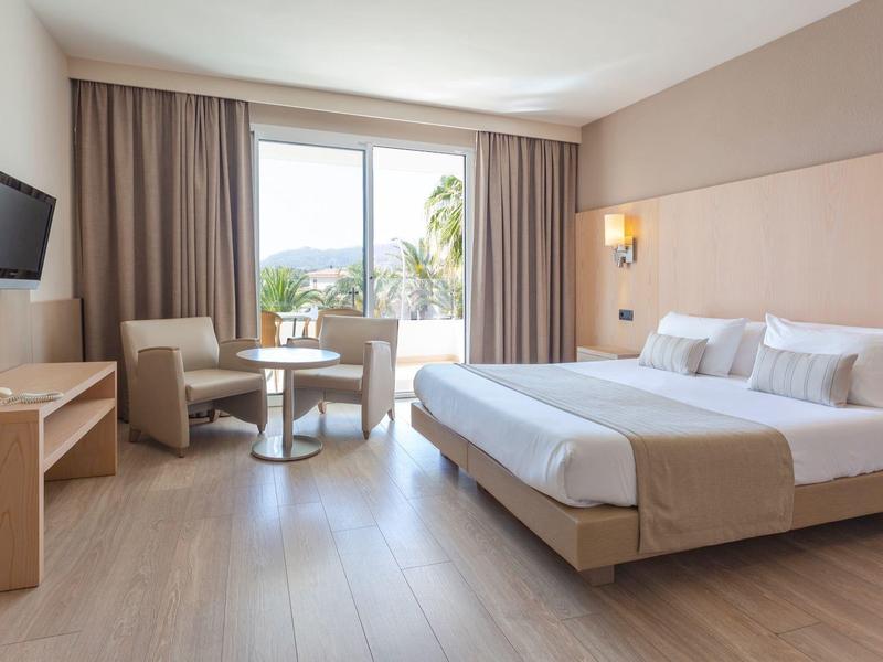 Pokój hotelowy z podwójnym łóżkiem, miejscem do siedzenia, telewizorem i balkonem z widokiem.