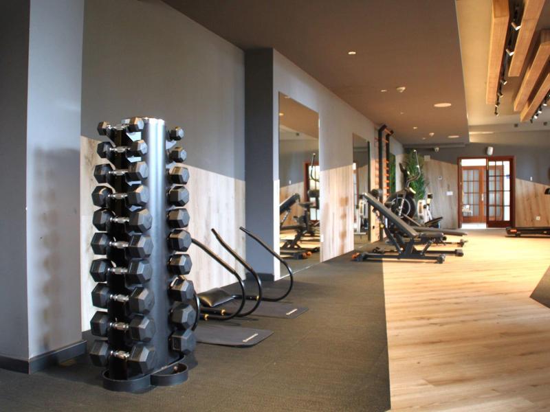 Nowoczesna siłownia hotelowa z hantlami, maszynami do ćwiczeń i naturalnym światłem