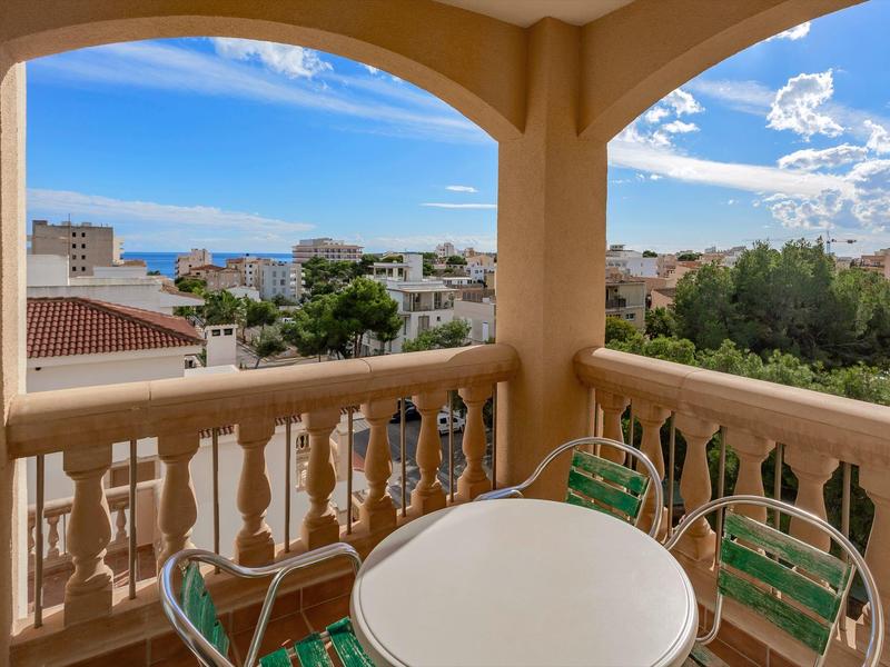 Balkon z okrągłym stołem, krzesłami i widokiem na morze z pokoju hotelowego.