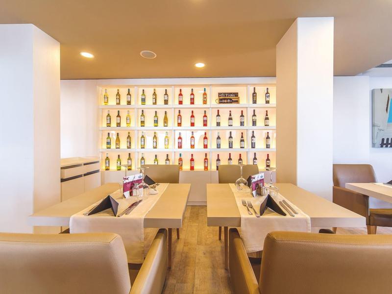 Nowoczesny hotelowy bar z podświetlanymi półkami z kolorowymi butelkami i wygodnymi miejscami do siedzenia.