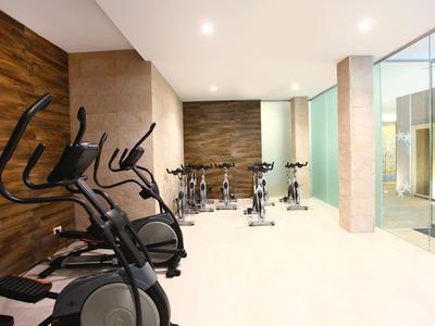 Sala fitness moderna con diverse cyclette e bike stazionarie di fronte a una parete in legno.