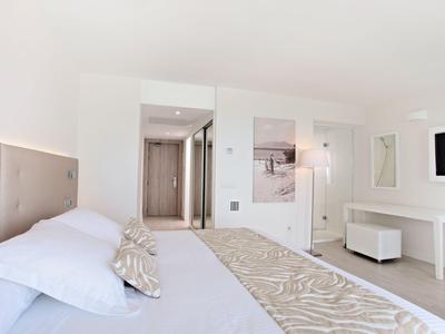Lichte, moderne hotelkamer met groot bed, flatscreen-tv en minimalistisch decor.
