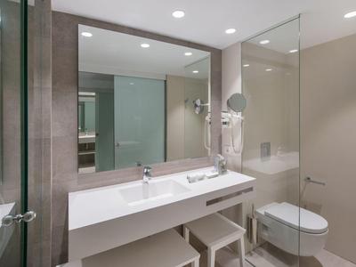 Modernes Badezimmer mit Glasdusche, weißem Waschbecken, Spiegeln und gedeckten Wandfarben.