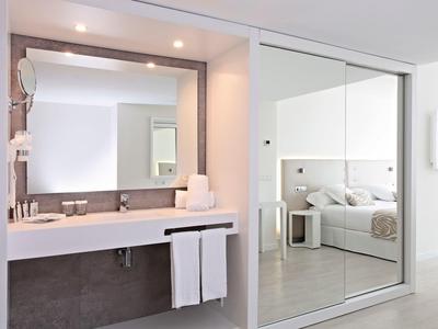 Moderne Badezimmerecke mit großem Spiegel, Waschbecken, Handtüchern und Glas-Schiebeschrank.