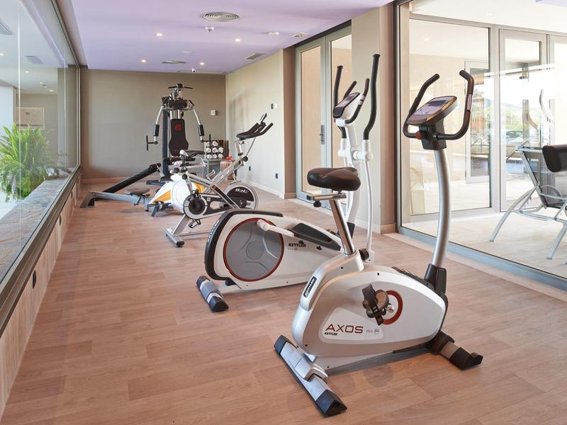 Attrezzi da palestra moderni in una palestra luminosa e spaziosa con pavimenti in legno e pareti di vetro.