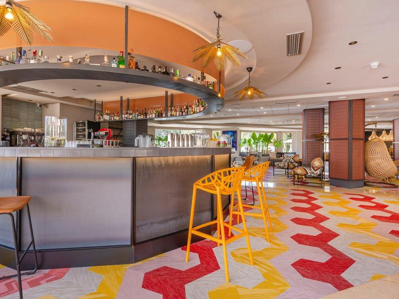 Area bar di un hotel moderno con pavimento geometrico colorato e mobili eleganti.