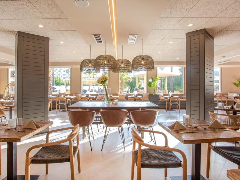 Ristorante luminoso e moderno con mobili in legno e grandi finestre in una giornata di sole.