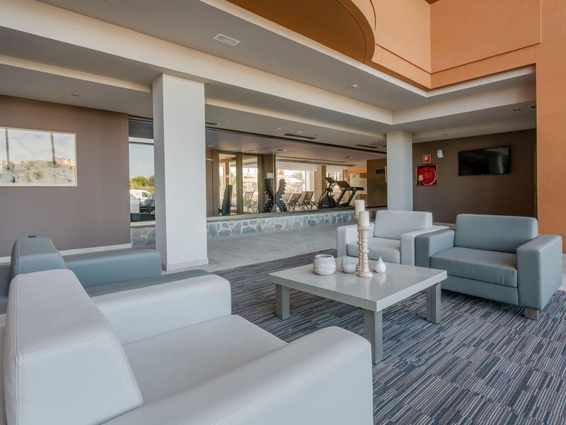 Area lounge moderna di hotel con poltrone bianche eleganti e tavolino su pavimento in moquette.