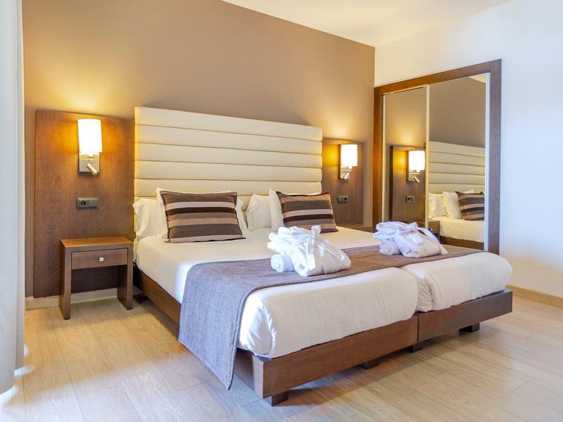 Camera doppia moderna con due letti, lampade da comodino e grande specchio.