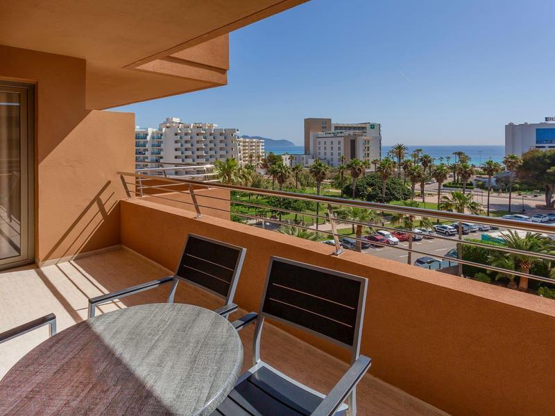 Balcone con tavolo e sedie con vista sulla città e sul mare sullo sfondo.