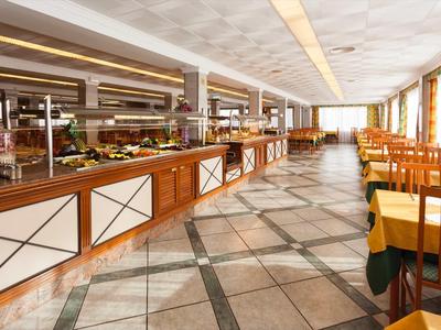 Duża jadalnia z bufetem i miejscami do siedzenia w ciepłych drewnianych tonach i obfitym naturalnym świetle.