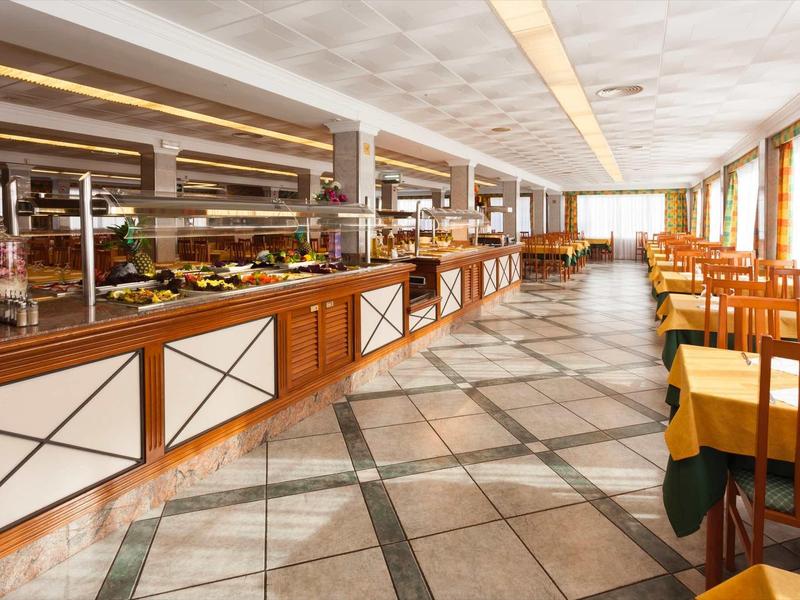 Large dining room with buffet and seating areas in warm wood tones and abundant natural light.