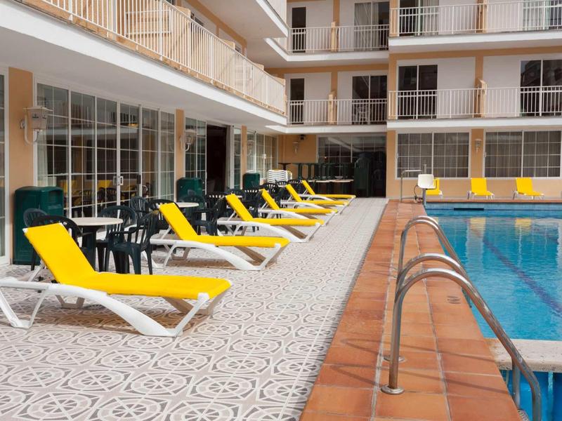 Swimming pool with yellow lounge chairs in a hotel courtyard.