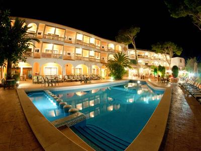 Hotel illuminato con piscina all'aperto e lettini di notte.