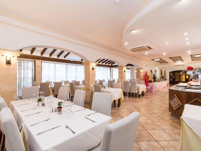 Ristorante luminoso apparecchiato formalmente con tovaglie bianche e sedie.