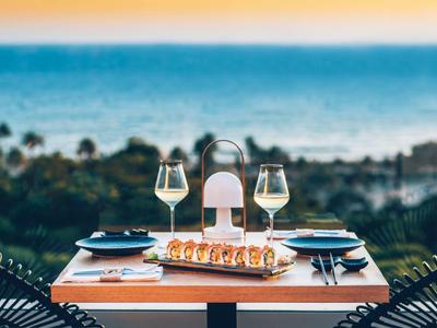 Table set with sushi and wine glasses overlooking sea and sunset