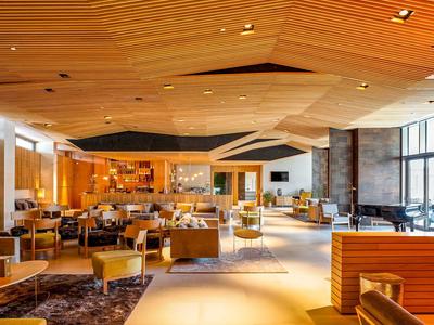 Spacious hotel lobby with modern wooden ceiling, comfortable seating, and warm lighting.